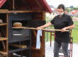 Frau holt Brot aus Backofen