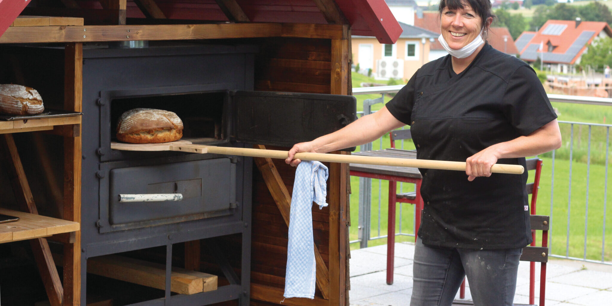 Frau holt Brot aus Backofen Frau holt Brot aus Backofen