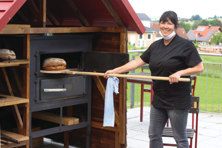Frau holt Brot aus Backofen Frau holt Brot aus Backofen