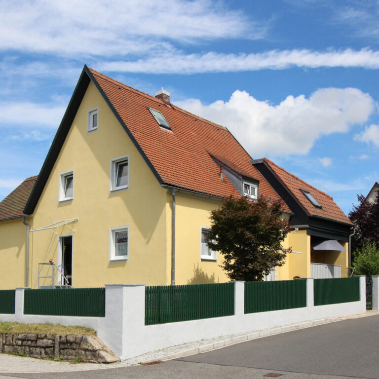WG Haus in Vohenstrauß von außen. Das Haus ist mit einem grünen Zaun umzäunt.