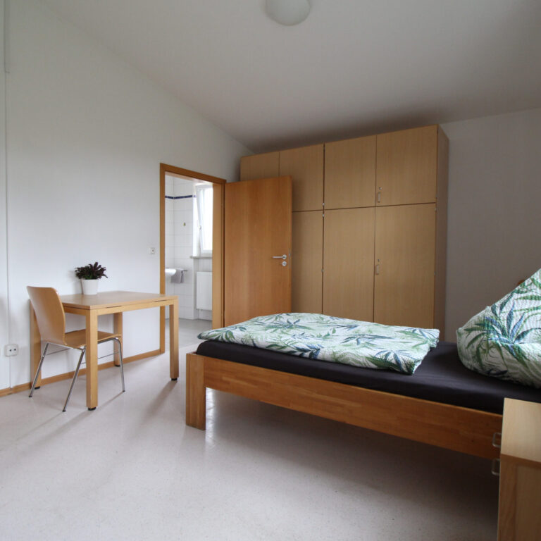 Stationäres Zimmer, mit Schränken, Bett, Tisch, Stuhl und offenem Fenster. Aus einem anderen Winkel Fotografiert