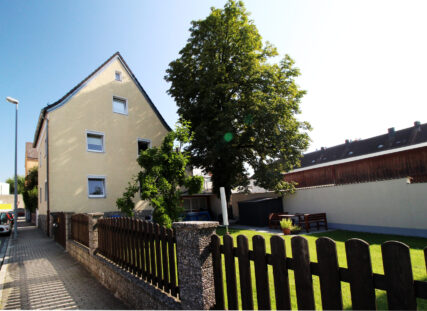 Gelbes Haus mit grünem, gepflegtem Garten