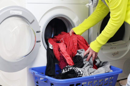 Wäsche wird in eine Waschmaschine gesteckt.