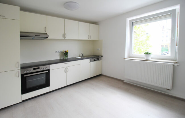Helle WG Küche in Weiden, das ein einige Schränke, einen Ofen, Herd und Spülmaschine enthält. Das Fenster ist groß und lässt viel Licht in die Küche