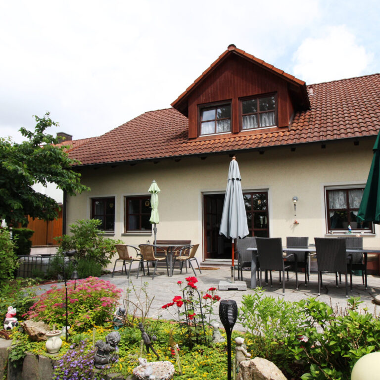Große Terrasse mit mehreren Tischen und Sonnenschirmen.