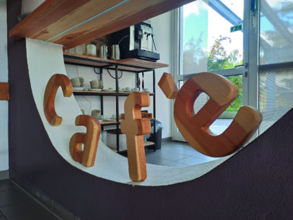 Das Wort "Café" ist aus Holzbuchstaben ausgeschnitten und im Halbkreis angeordnet worden.