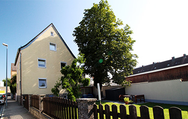 Gelbes Haus mit grünem, gepflegtem Garten