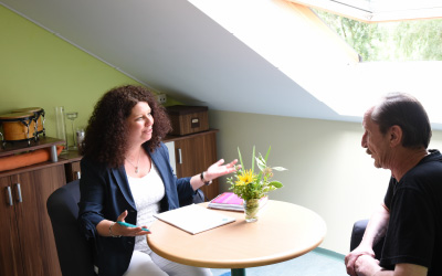 Mann wird von Frau an einem Tisch beraten.